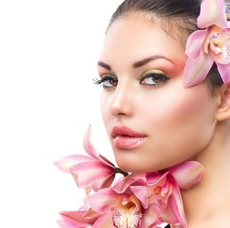 Schöne Frau mit rosa Blumen im Gesicht, die die Wirkung von Radiofrequenzlifting zeigt: straffen, liften, glätten.